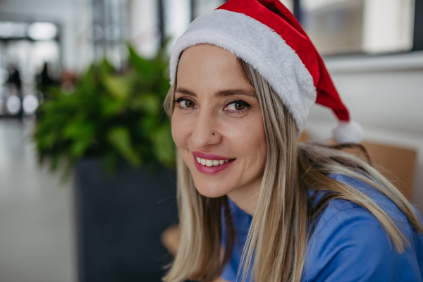 Beautiful nurse with christmas hat sitting in hospital waiting room, corridor. Obstetrics nurse working in hospital on the Christmas day, Christmas Eve. Female doctor working a Christmas shift and can't be with her family.