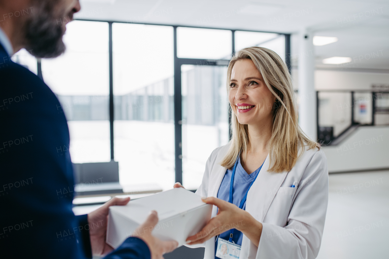 Pharmaceutical sales representative presenting new medication, pills to doctor in medical building.