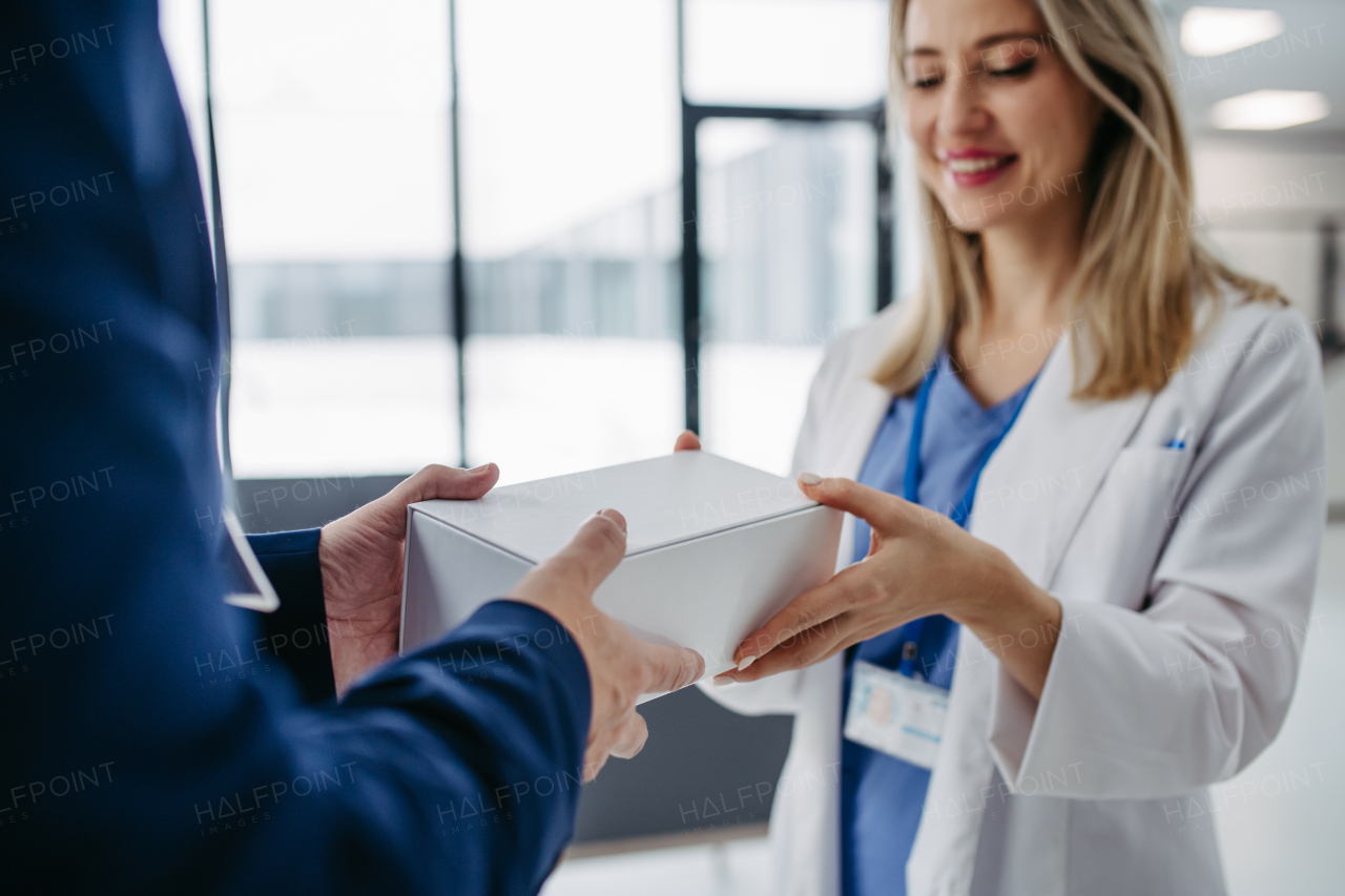 Pharmaceutical sales representative presenting new medication, pills to doctor in medical building.