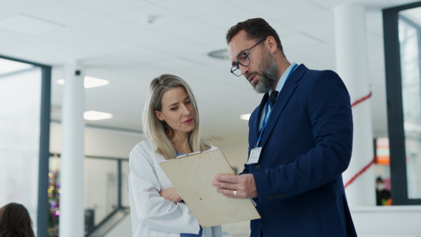 Pharmaceutical sales representative talking with doctor in medical building. Female doctor talking with hospital director, manager in the private clinic.