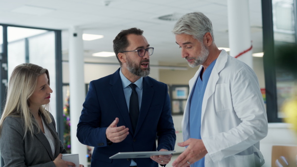 Pharmaceutical sales representatives meeting doctor in medical building. Hospital director and manager talking with head physician in modern medical clinic, hospital.