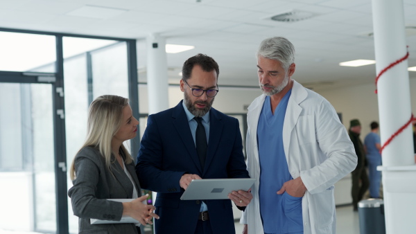 Pharmaceutical sales representatives meeting doctor in medical building. Hospital director and manager talking with head physician in modern medical clinic, hospital.