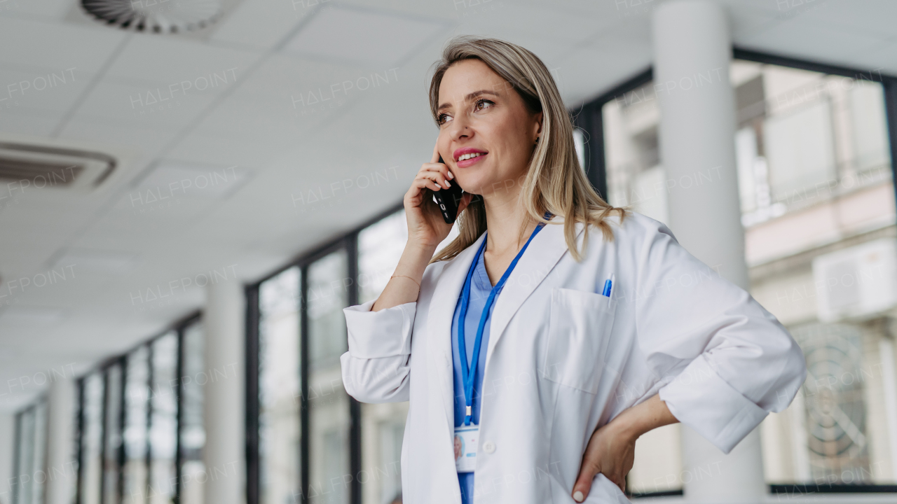 Portrait of beautiful ER doctor in hospital phone calling. Remote consultations with patient, telemedicine.