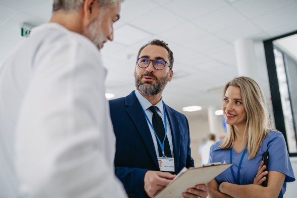 Pharmaceutical sales representative talking with doctors in medical building, drug rep presenting new pharmaceutical product, drug.