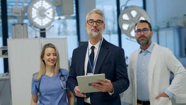 Portrait of pharmaceutical sales representative standing in doctor office. Hospital director, manager of private medical clinic greeting new doctors. Generous donor, giving donation to hospital. Through door.