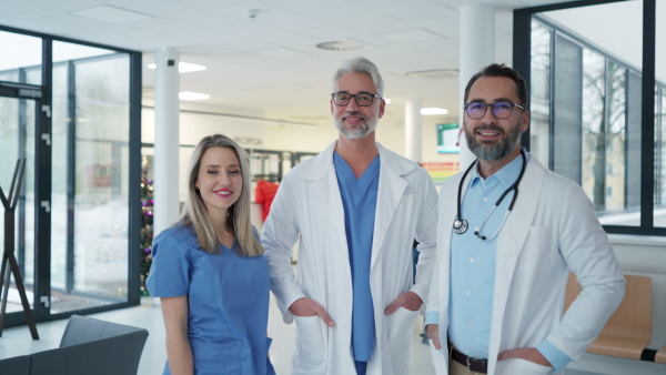 Video of female doctor standing in front of male colleagues. Beautiful nurse in uniform, standing in modern private clinic, looking at camera.