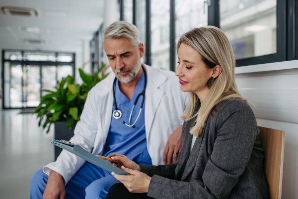 Pharmaceutical sales representative talking with doctor in medical building. Female medical rep presenting new medication. Female hospital director with medical director.