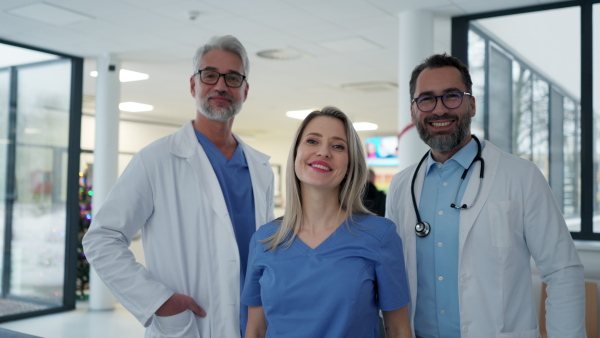 Video of female doctor standing in front of male colleagues. Beautiful nurse in uniform, standing in modern private clinic, looking at camera.