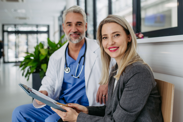 Female pharmaceutical sales representative presenting new medication, pills to doctor in medical building, looking at camera