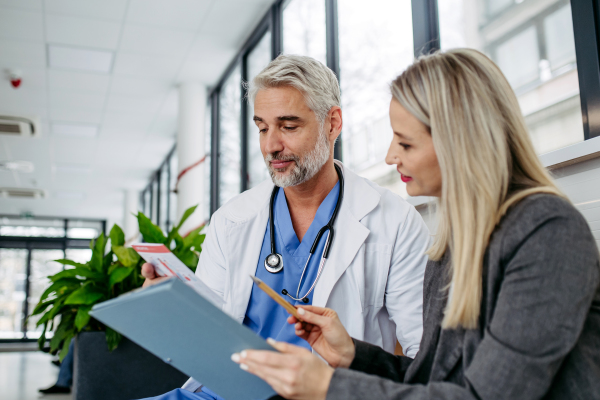 Pharmaceutical sales representative talking with doctor in medical building. Female medical rep presenting new medication. Female hospital director with medical director.