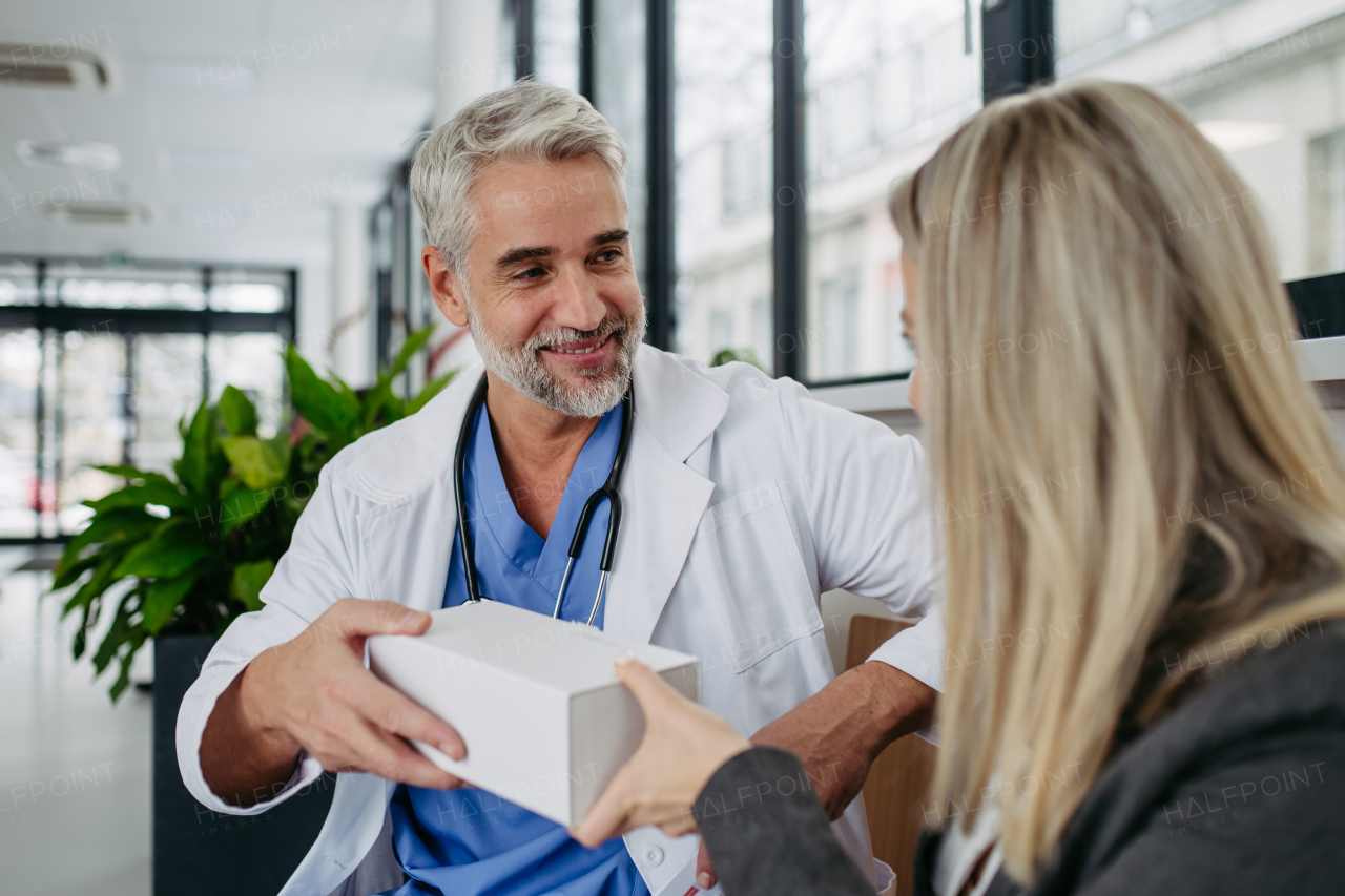 Female pharmaceutical sales representative presenting new medication, pills to doctor in medical building.