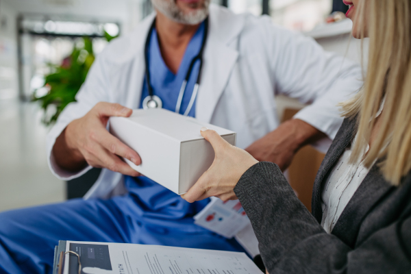 Female pharmaceutical sales representative presenting new medication, pills to doctor in medical building.