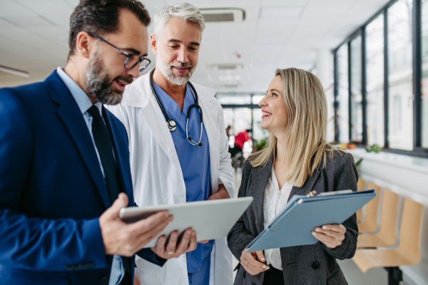 Pharmaceutical sales representatives meeting doctor in medical building. Hospital director and manager talking with head physician in modern medical clinic, hospital.