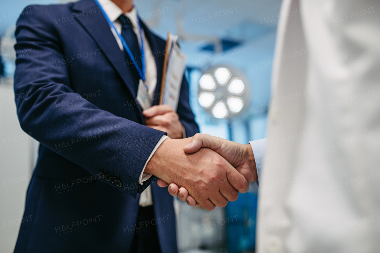 Portrait of pharmaceutical sales representative standing in doctor office, shaking hands. Hospital director, manager of private medical clinic greeting new doctor. Generous donor, giving donation to hospital.