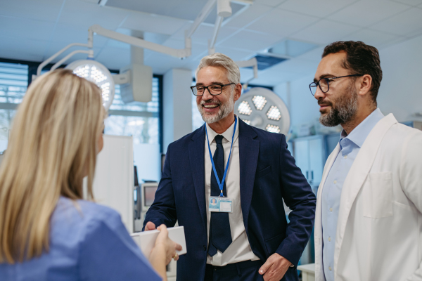 Portrait of pharmaceutical sales representative standing in doctor office. Hospital director, manager of private medical clinic greeting new doctors. Generous donor, giving donation to hospital.