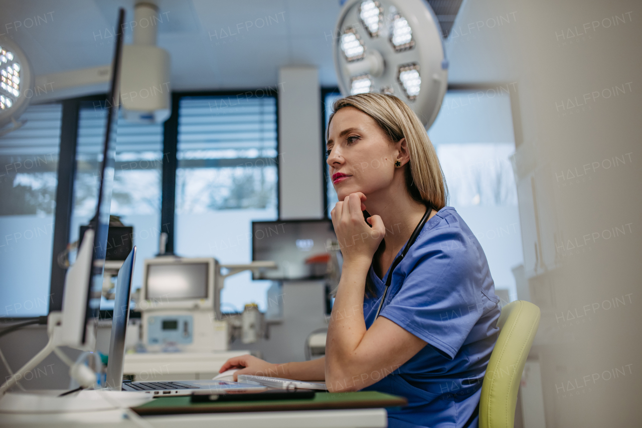 Side view of female ER doctor in hospital working in emergency room. Healthcare worker looking at MRI scan on medical computer in emergency room.