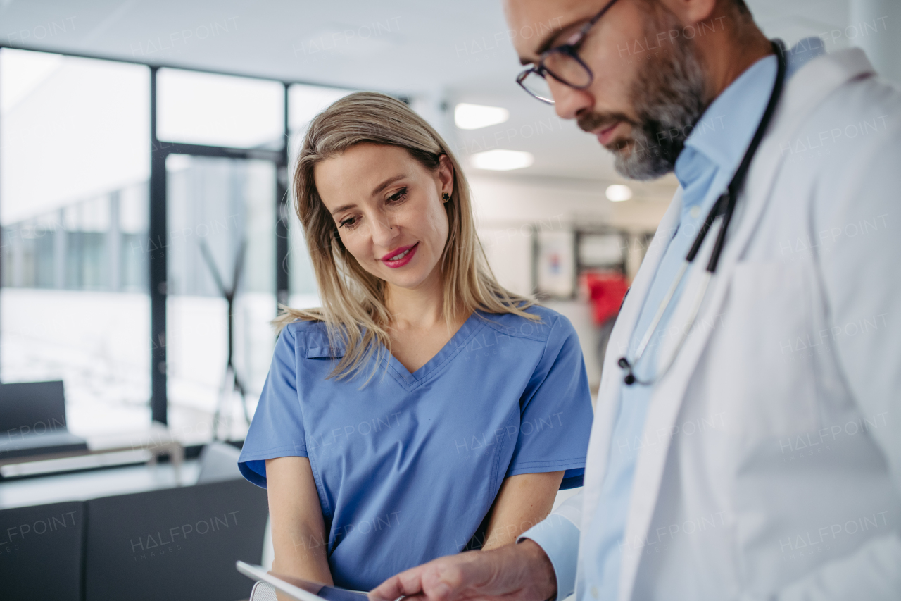 Doctor and nurse looking at test results on tablet, talking about patients diagnosis. Portrait of beautiful nurse.