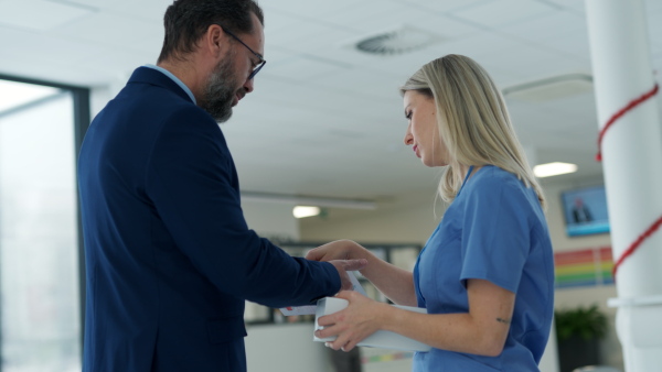 Pharmaceutical sales representative talking with doctor in medical building. Female doctor talking with hospital director, manager in the private clinic.