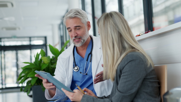 Pharmaceutical sales representative talking with doctor in medical building. Female medical rep presenting new medication. Female hospital director with medical director.