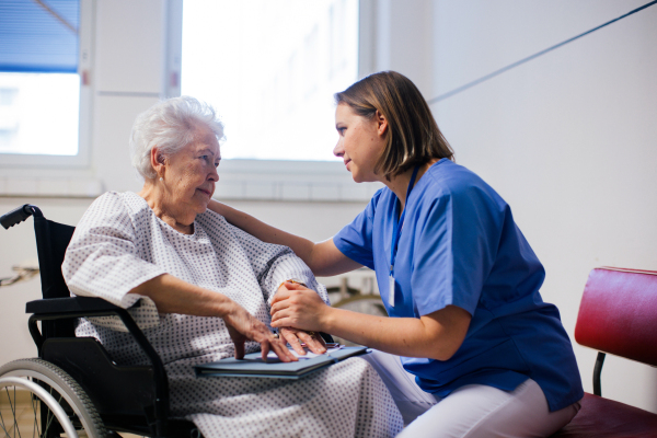 Nurse comforting a scared elderly patient in a wheelchair. Senior woman waiting for examination in the hospital.