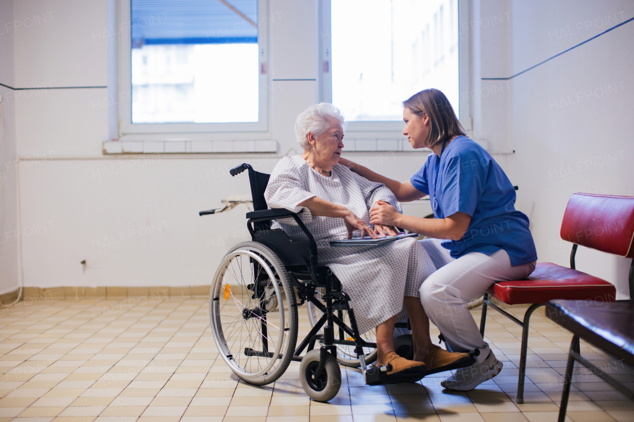 Nurse soothing woried elderly patient in a wheelchair. Senior woman waiting for examination in the hospital.