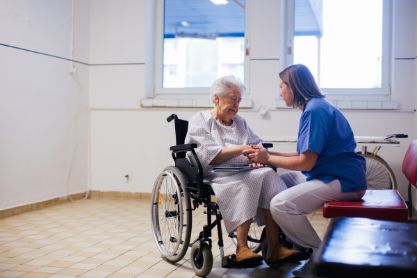 Nurse comforting a scared elderly patient in a wheelchair. Senior woman waiting for examination in the hospital.