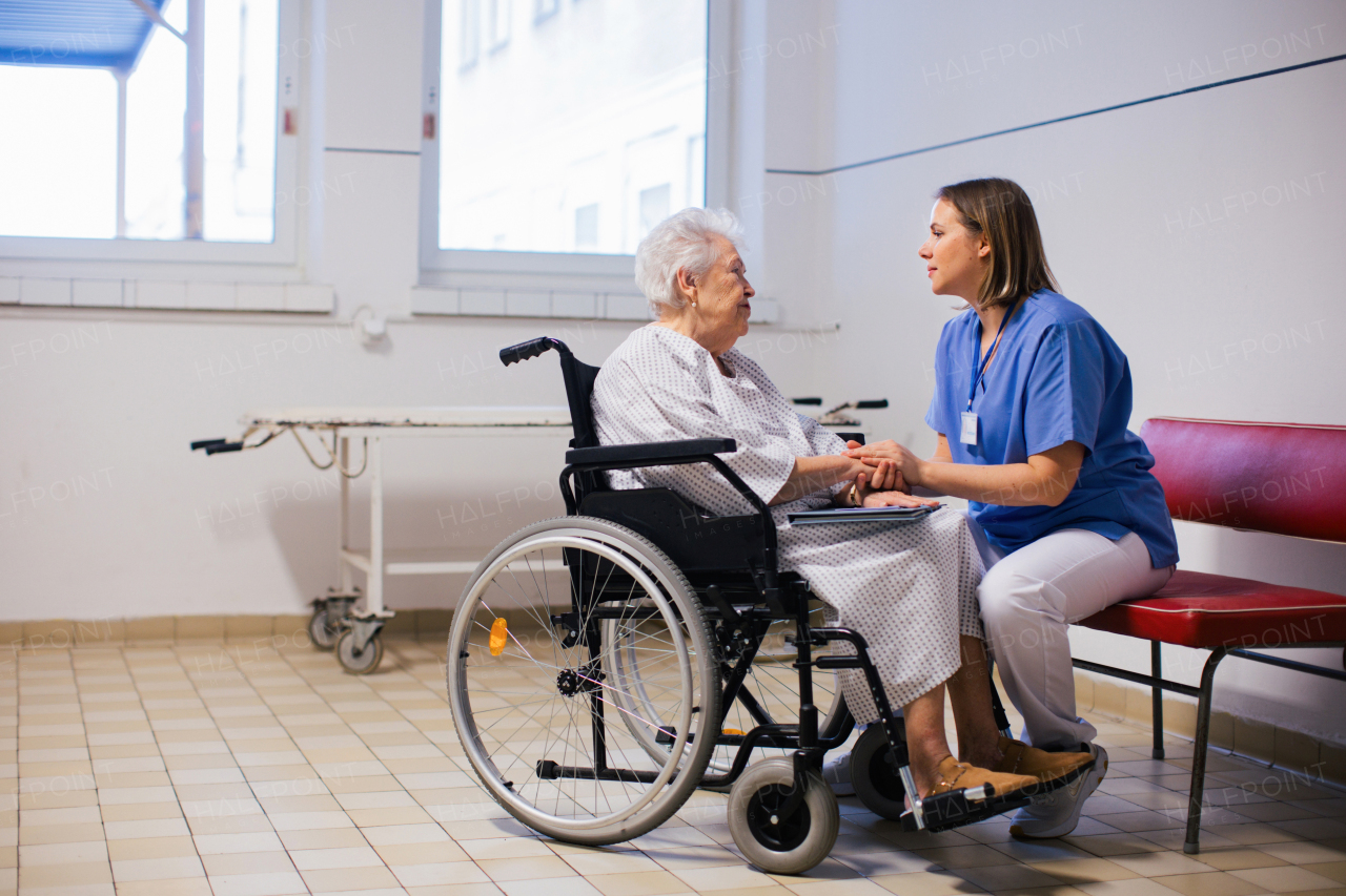 Nurse comforting a scared elderly patient in a wheelchair. Senior woman waiting for examination in the hospital. Emotional support for senior woman.