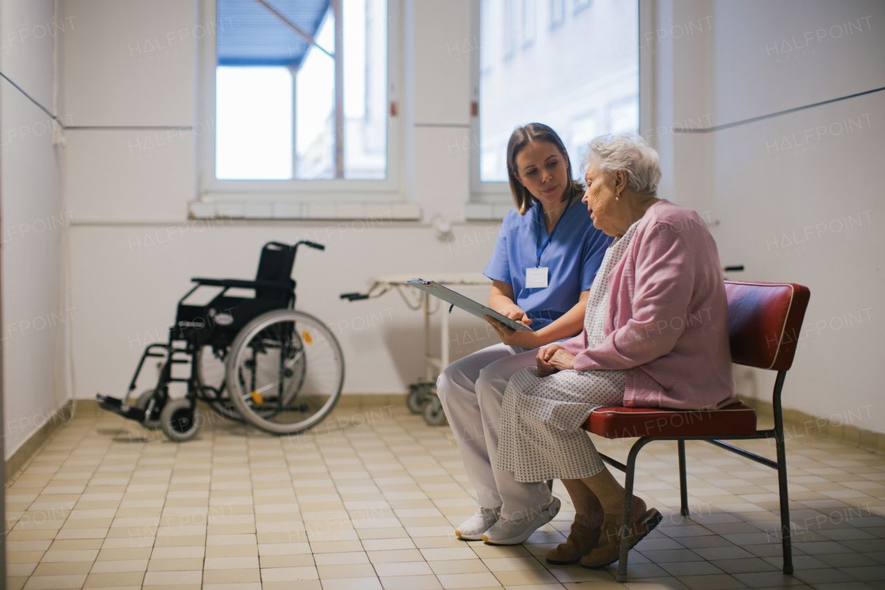 Senior patient talking with nurse, scheduling date and time of next examination. Doctor explaining test resulst, emotional support for elderly woman in hospital.