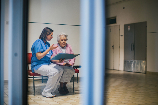 Senior patient talking with nurse, scheduling date and time of next examination. Doctor explaining test resulst, emotional support for elderly woman in hospital.