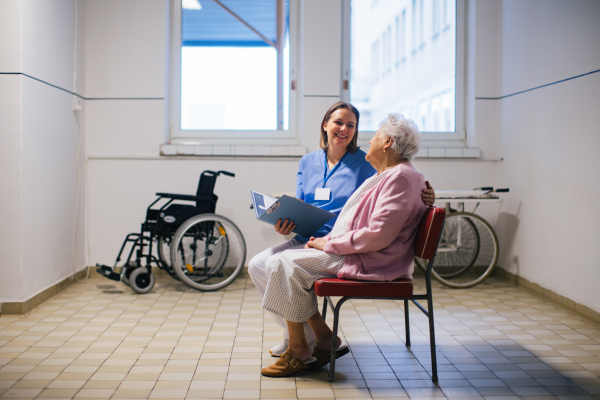 Senior patient talking with nurse, scheduling date and time of next examination. Doctor explaining test resulst, emotional support for elderly woman in hospital.