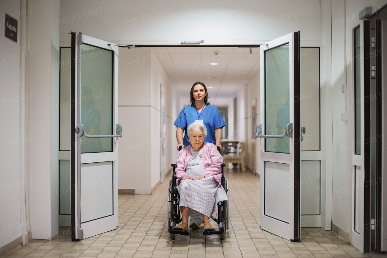 Nurse pushing scared senior patient in a wheelchair down an outdated hospital corridor. Elderly woman in hospital gown going for surgery, feeling anxious.