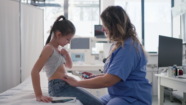 Nurse injecting insulin in diabetic young girl belly. Close up of young girl with type 1 diabetes taking insuling with syringe needle.