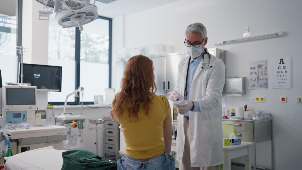 Doctor, pediatrician injecting vaccine into teenage girl arm, routine vaccinations. Concept of preventive health care for adolescents.