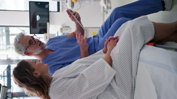 Doctor showing female patient MRI scan on tablet, discussing her test result in emergency room.