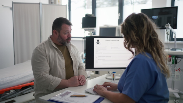 Female doctor consulting with overweight patient, discussing test result and x-ray scans in doctor office. Concept of health risks of overwight and obesity.