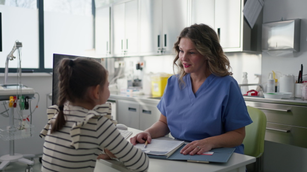 Young girl visiting pediatrician doctor, discussing test results. Concept of preventive health care for adolescents.