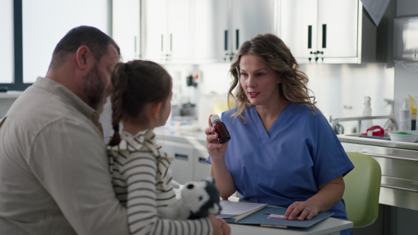 Female Doctor explaining test results to father of young girl patient. Concept of children healthcare and emotional support for child patients.