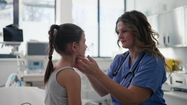 Female doctor examining lymp nodes on neck of the young girl. Palpation of lymph nodes. Concept of preventive health care for childre