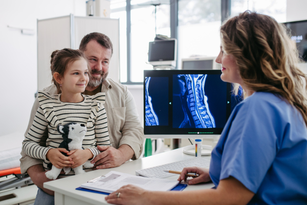 Female Doctor explaining test results to father of young girl patient. Concept of children healthcare and emotional support for child patients.