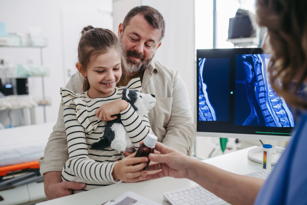 Female Doctor explaining test results to father of young girl patient. Concept of children healthcare and emotional support for child patients.