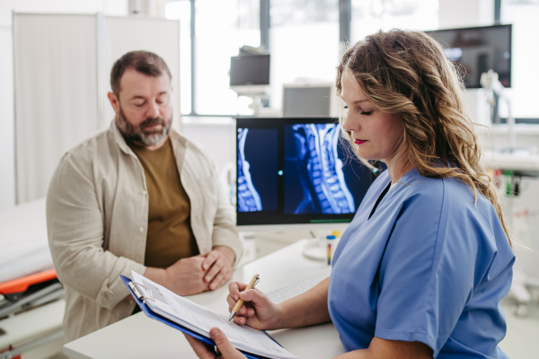 Female doctor consulting with overweight patient, discussing test result and x-ray scans in doctor office. Concept of health risks of overwight and obesity.