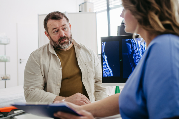 Female doctor consulting with overweight patient, discussing test result and x-ray scans in doctor office. Concept of health risks of overwight and obesity.