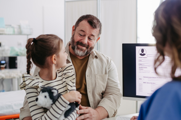 Female Doctor explaining test results to father of young girl patient. Concept of children healthcare and emotional support for child patients.