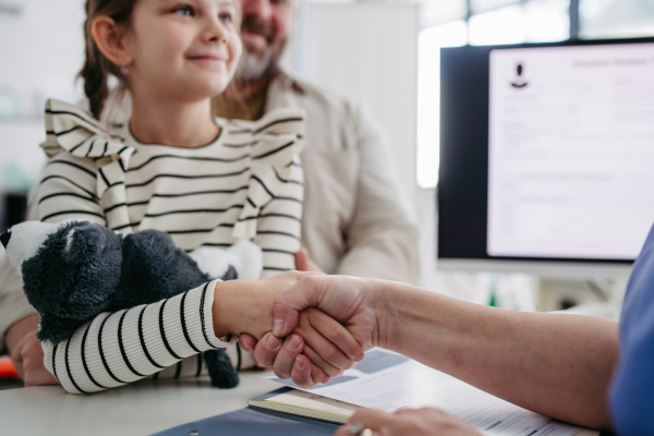 Female Doctor greeting young girl patient, handshake. Concept of children healthcare and emotional support for child patients.