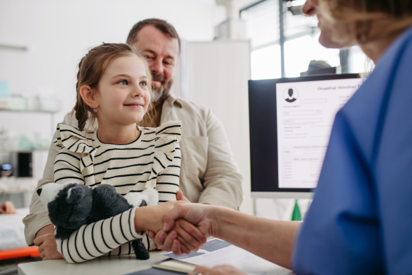 Female Doctor greeting young girl patient, handshake. Concept of children healthcare and emotional support for child patients.