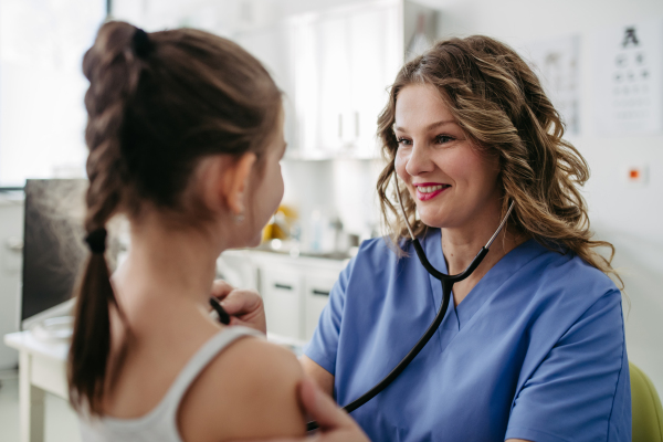 Orthopedist examines the spine, posture, and spinal deformities of little girl. Girl visiting paediatrician for annual preventive physical examination. Concept of preventive health care for children.