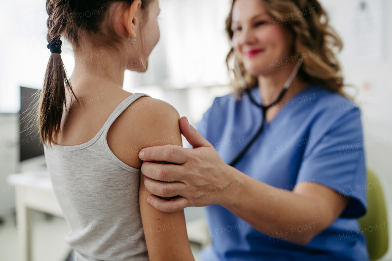 Orthopedist examines the spine, posture, and spinal deformities of little girl. Girl visiting paediatrician for annual preventive physical examination. Concept of preventive health care for children.