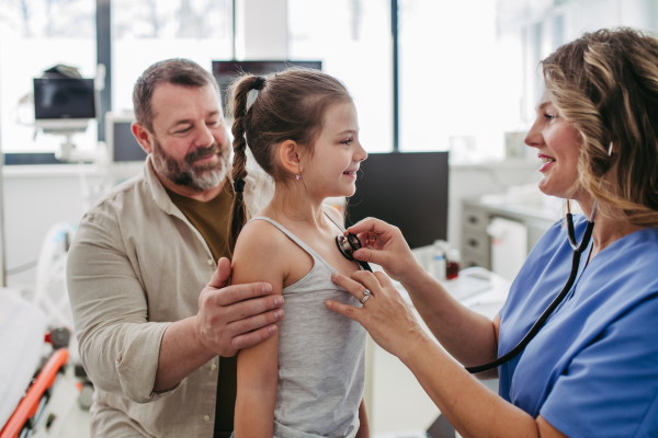 Female Doctor examining young girl, listening to heartbeat, breathing, using stethoscope. Concept of preventive health care for children.