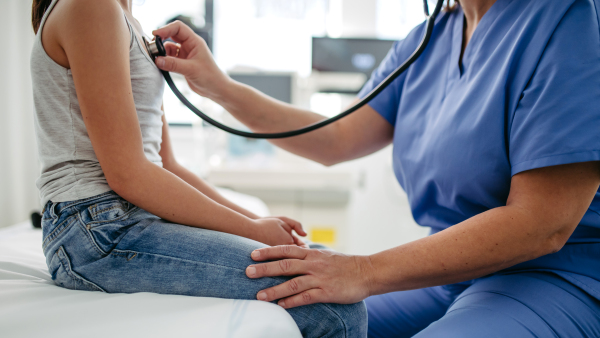 Orthopedist examines the spine, posture, and spinal deformities of little girl. Girl visiting paediatrician for annual preventive physical examination. Concept of preventive health care for children.