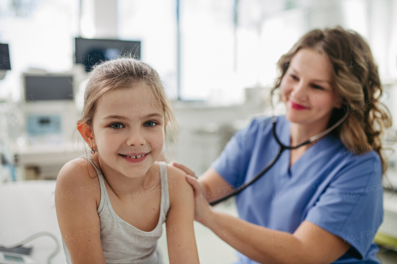 Orthopedist examines the spine, posture, and spinal deformities of little girl. Girl visiting paediatrician for annual preventive physical examination. Concept of preventive health care for children.